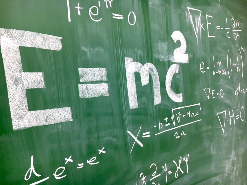 Green chalkboard filled with white chalk equations and symbols from a math lesson.