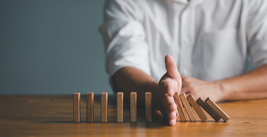 Risk and Strategy in Business Hand stopping wooden block domino business crisis effect or risk protection concept prevention and development to stability - Semicon.TODAY