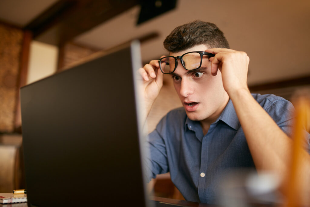 Shocked freelancer hipster man looks to laptop screen and can not believe unpleasant news Pop-eyed frightened businessman trader raises ones glasses above his eyes Trader monitoring stock exchange - Semicon.TODAY