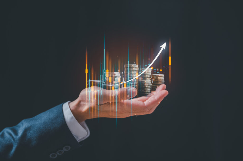 investment and finance concept businessman holding virtual trading graph and blurred coins on hand stock market profits and business growth - Semicon.TODAY