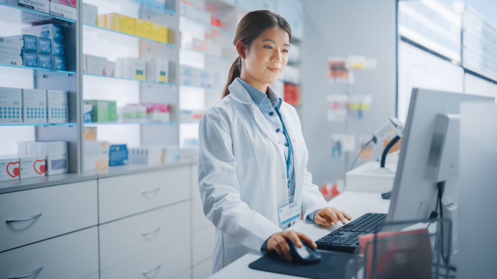 Pharmacy Drugstore Beautiful Asian Pharmacist Uses Checkout Counter Computer Does Inventory Checkup Online Prescription of Medicine Packages Drugs Vitamin Boxes Supplements Health Care Products - SEMICON.TODAY