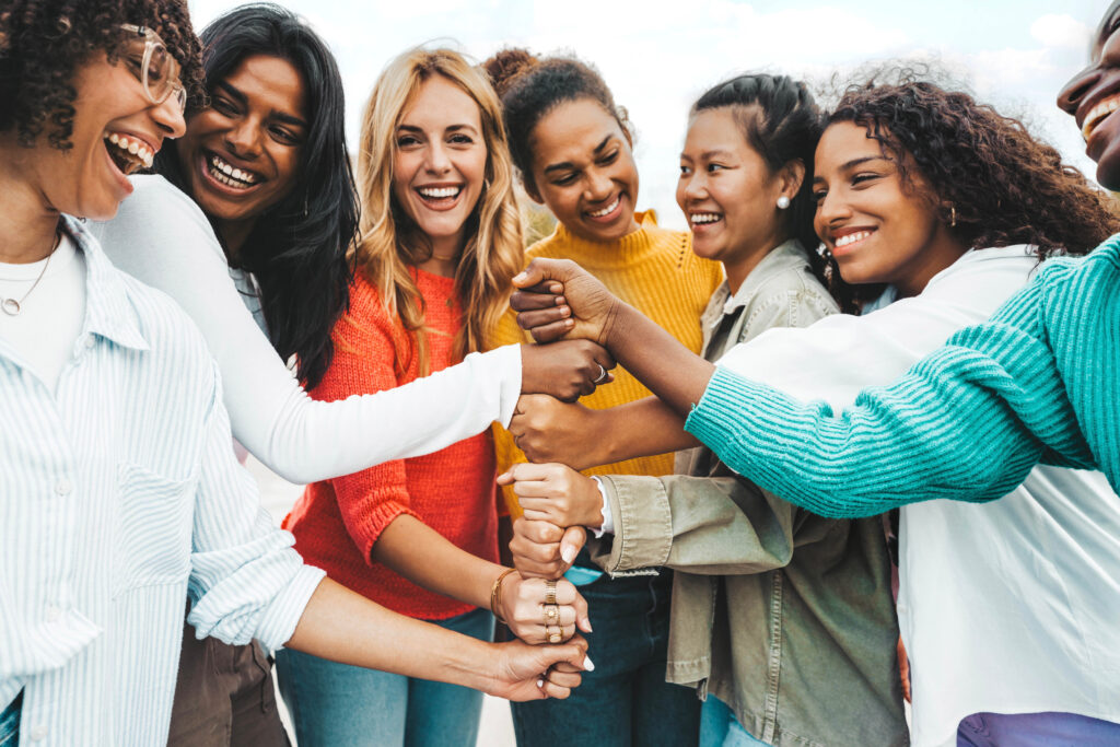 Multicultural group of women stacking hands together - Female community concept with different girls support each other - Girlfriends hugging outdoors - SEMICON.TODAY