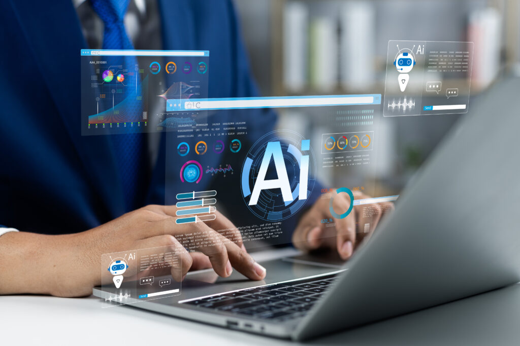 Businessman use artificial intelligence AI technology for enhanced work efficiency data analysis and efficient tools Unlocking work potential with AI solutions chatbot help solve work problems - SEMICON.TODAY Hands typing on a laptop with translucent AI data holograms showing charts and a small robot icon.”,