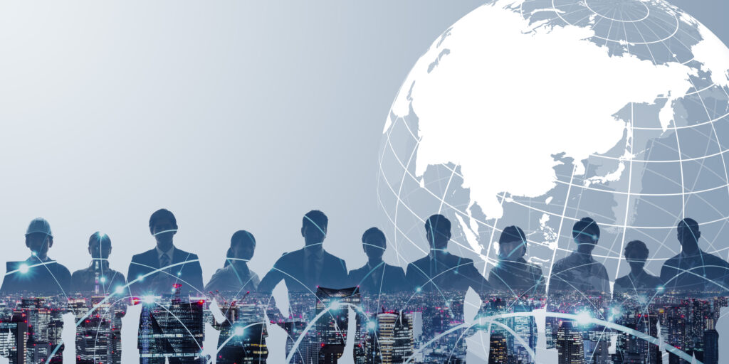 Silhouetted businesspeople standing before a city skyline and a stylized globe with network lines, symbolizing global connectivity.
