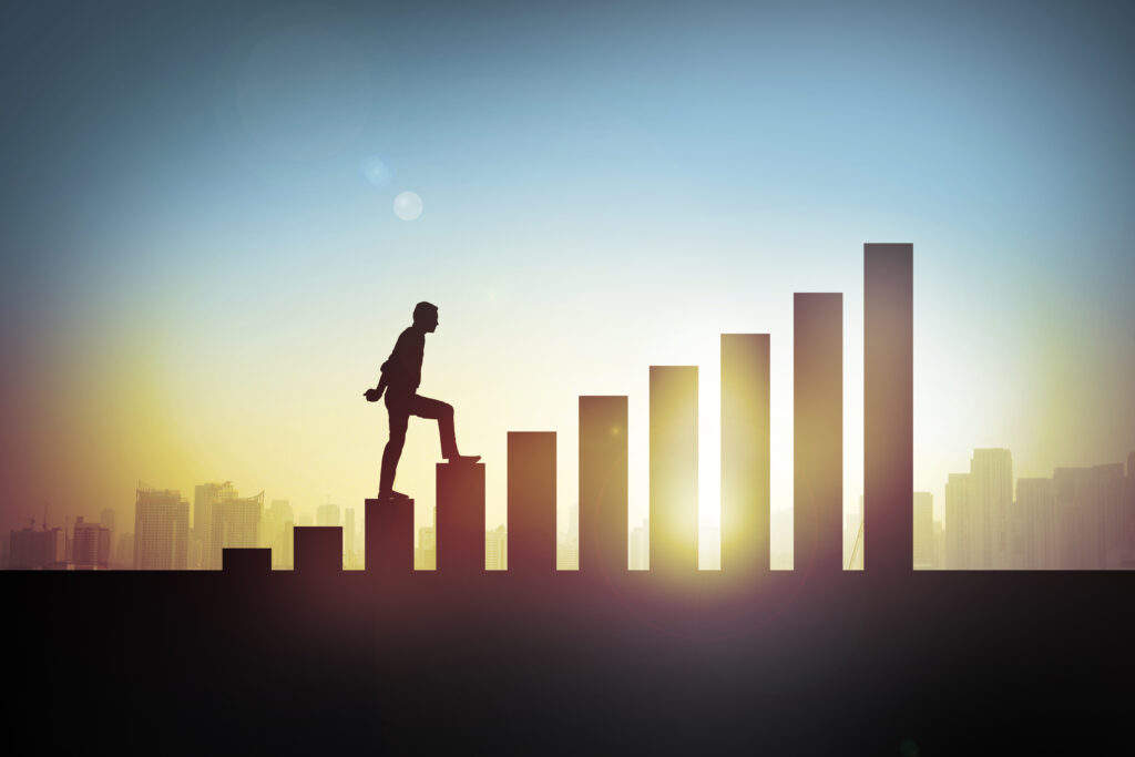 Silhouette of a person climbing a staircase that doubles as ascending bars, with a city skyline at sunset in the background