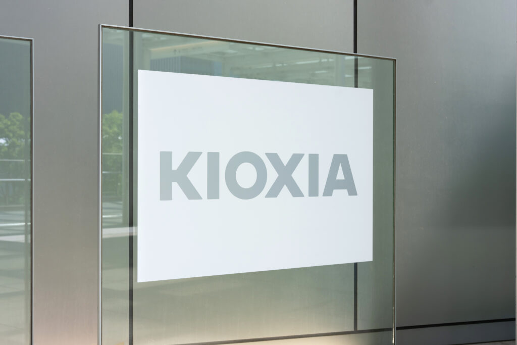White sign reading KOXA mounted on a glass storefront of a modern gray building.