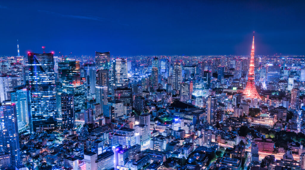 Nighttime cityscape of Tokyo with illuminated skyscrapers and the red-lit Tokyo Tower on the right.