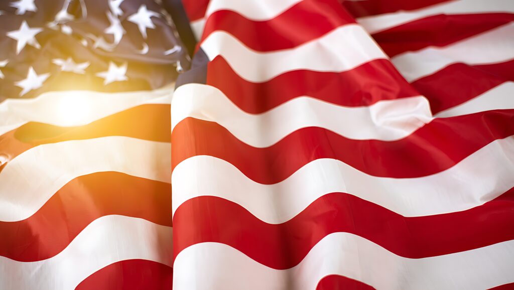 American flag waving close-up of stars and stripes with soft vintage light overlay - SEMICON.TODAY American flag waving in warm sunlight, red and white stripes visible in the breeze