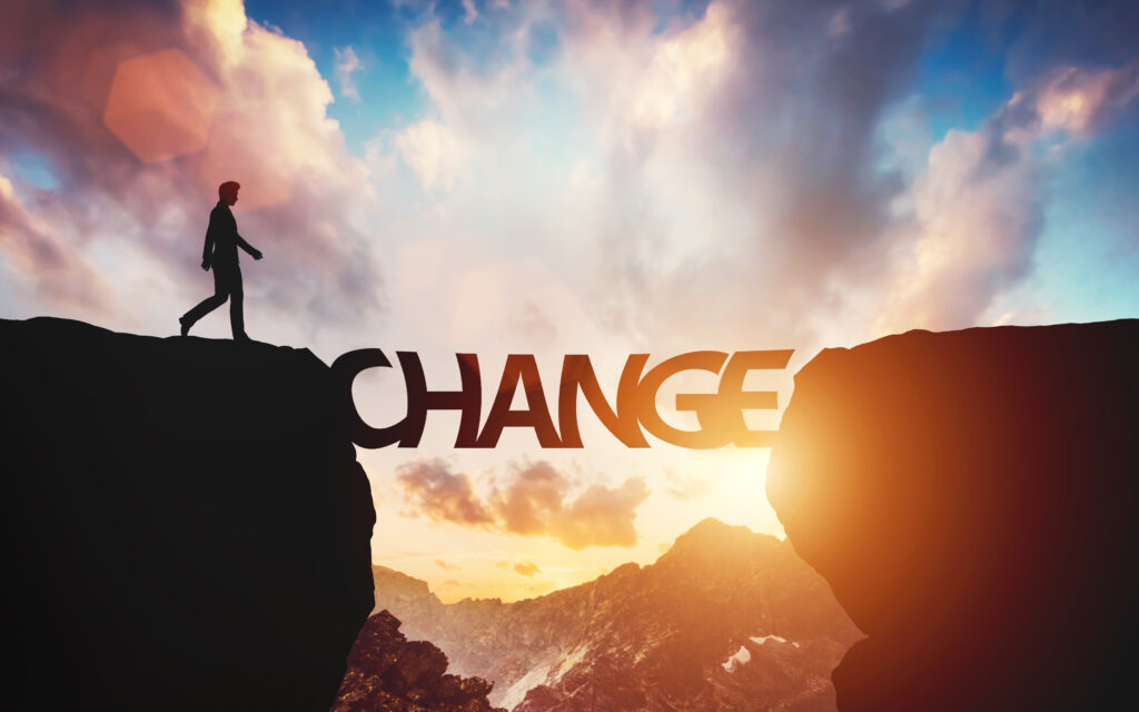 Change concept Man walking on the other side of mountain - SEMICON.TODAY Silhouette of a person walking along a rocky cliff at sunrise, with the word CHANGE spanning the lower foreground.